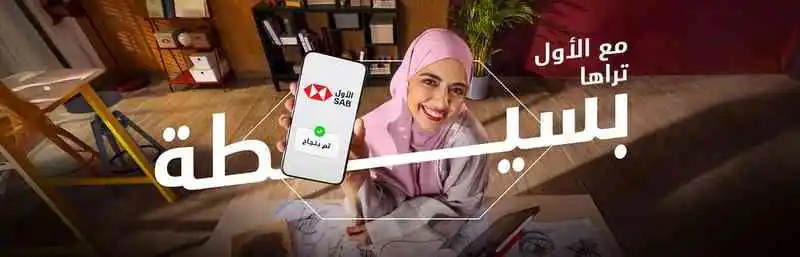 مصممة أزياء سعودية في مكتبها تعرض هاتفها مكتوب عليه كلمة "بسيطة" باللغة العربية